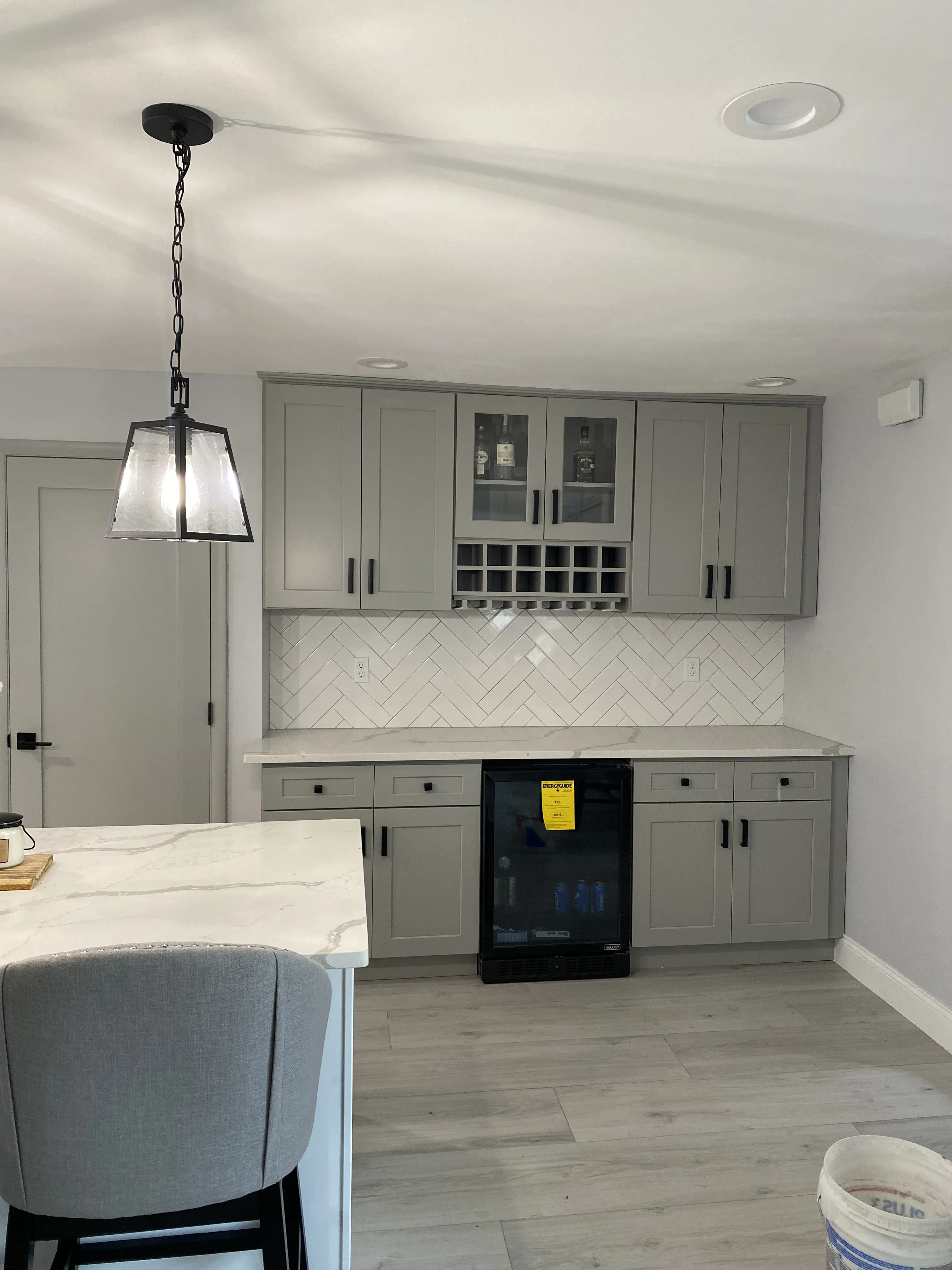 Custom dry bar with gray shaker cabinetry, herringbone tile backsplash, built-in wine fridge and pendant lighting by Zavala & Sons