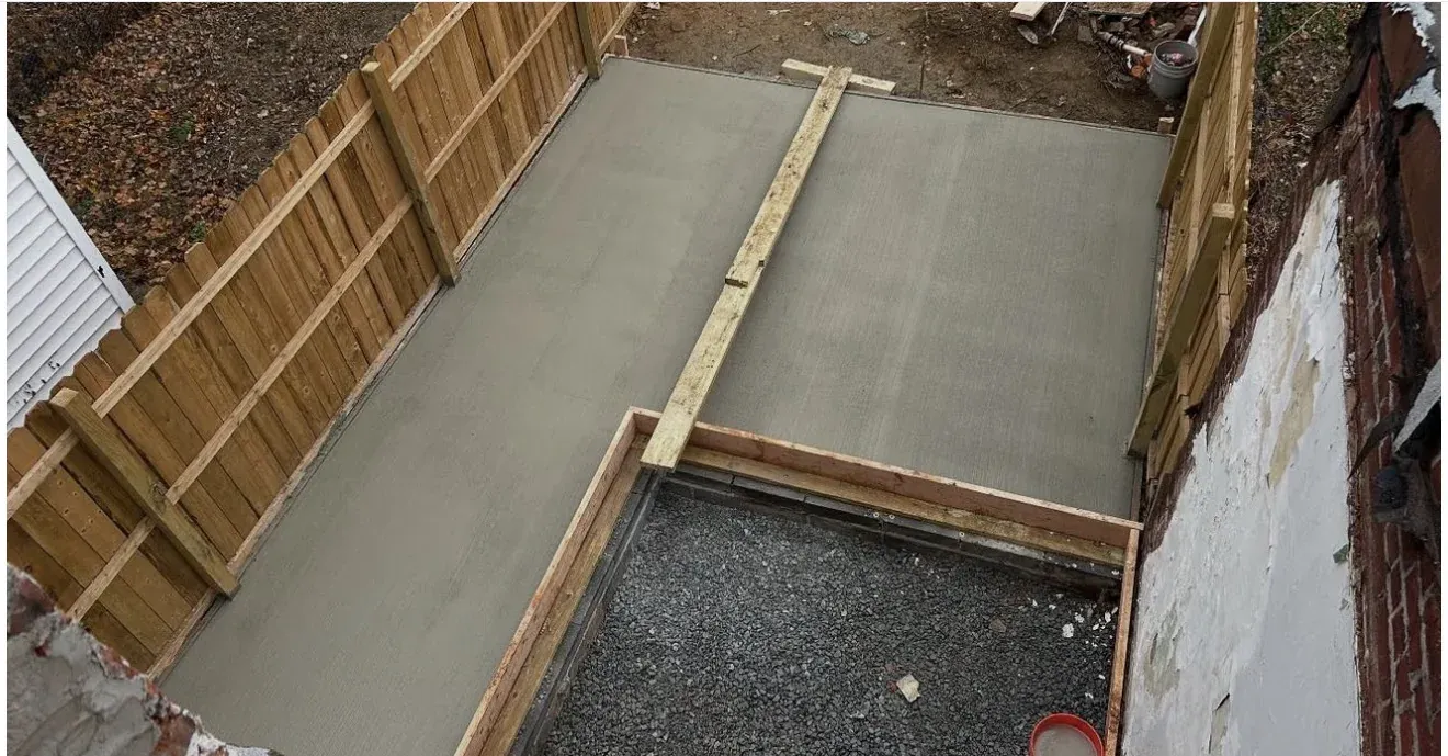 Concrete slab with wood forms set between privacy fence — side-yard pad pour by Zavala & Sons concrete crew