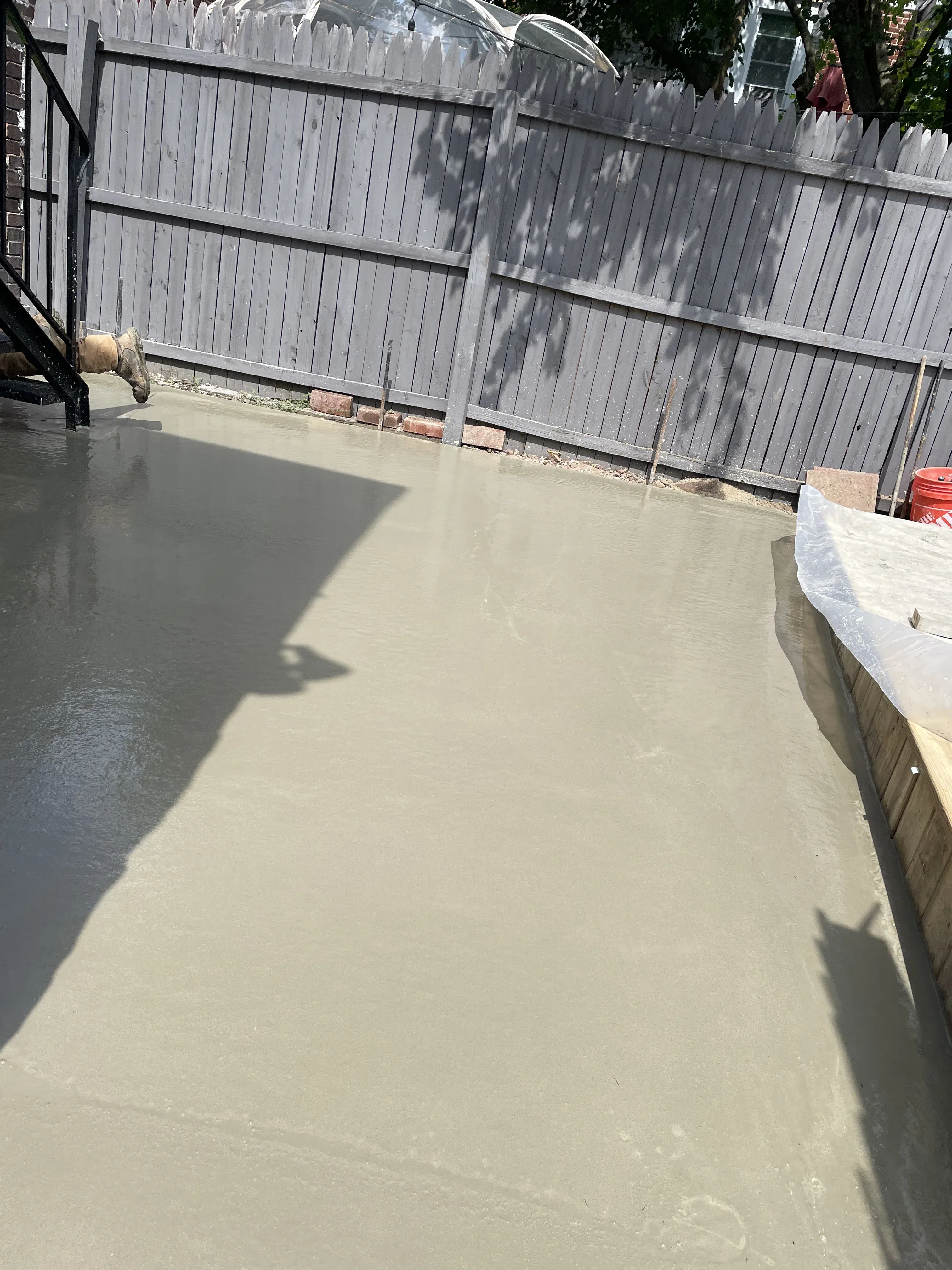 Concrete patio pour against privacy fence with hand-tooled edges — backyard concrete flatwork by Zavala & Sons