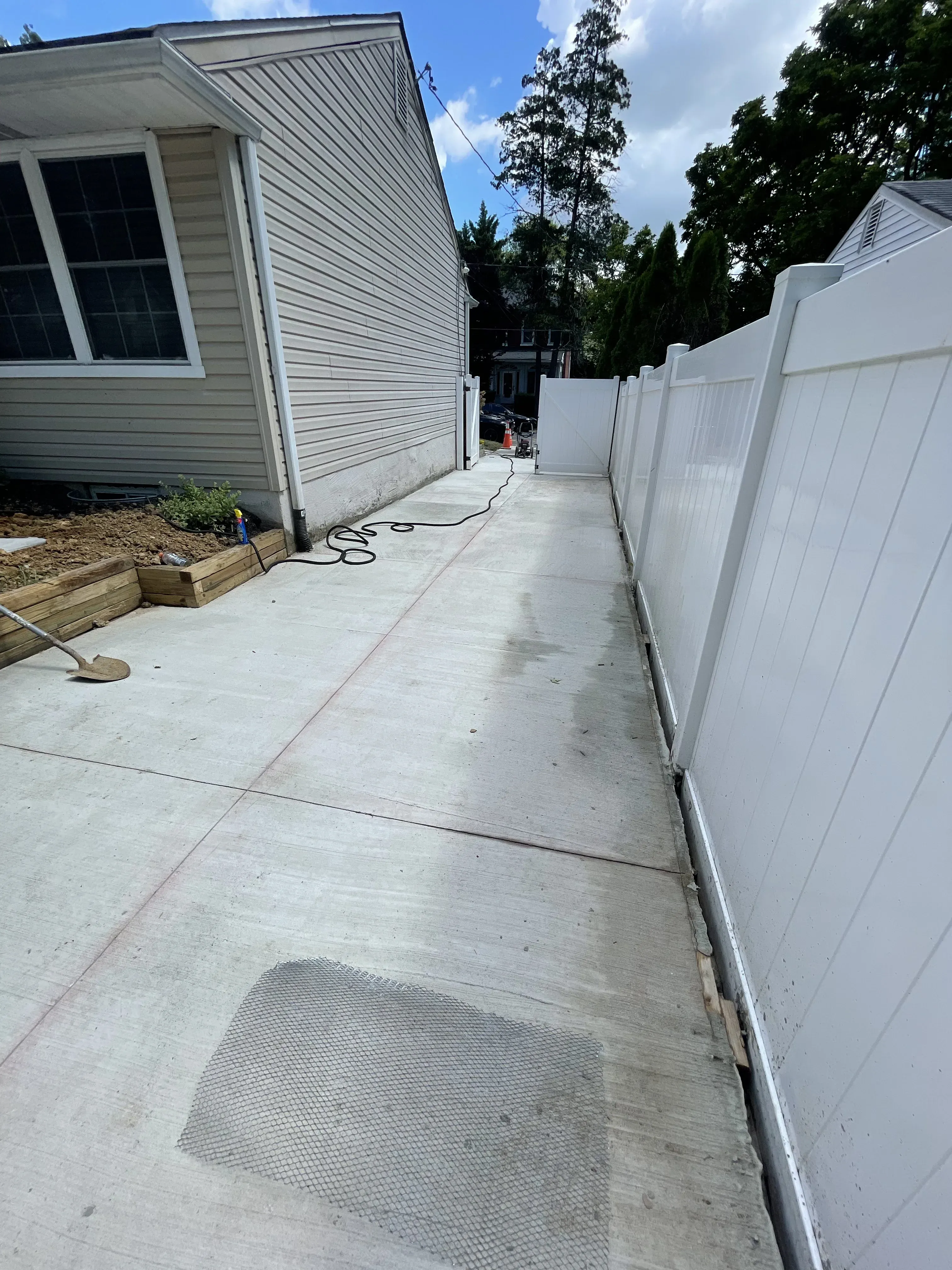 Concrete side-yard walkway between house and vinyl privacy fence — residential concrete by Zavala & Sons Wilmington DE