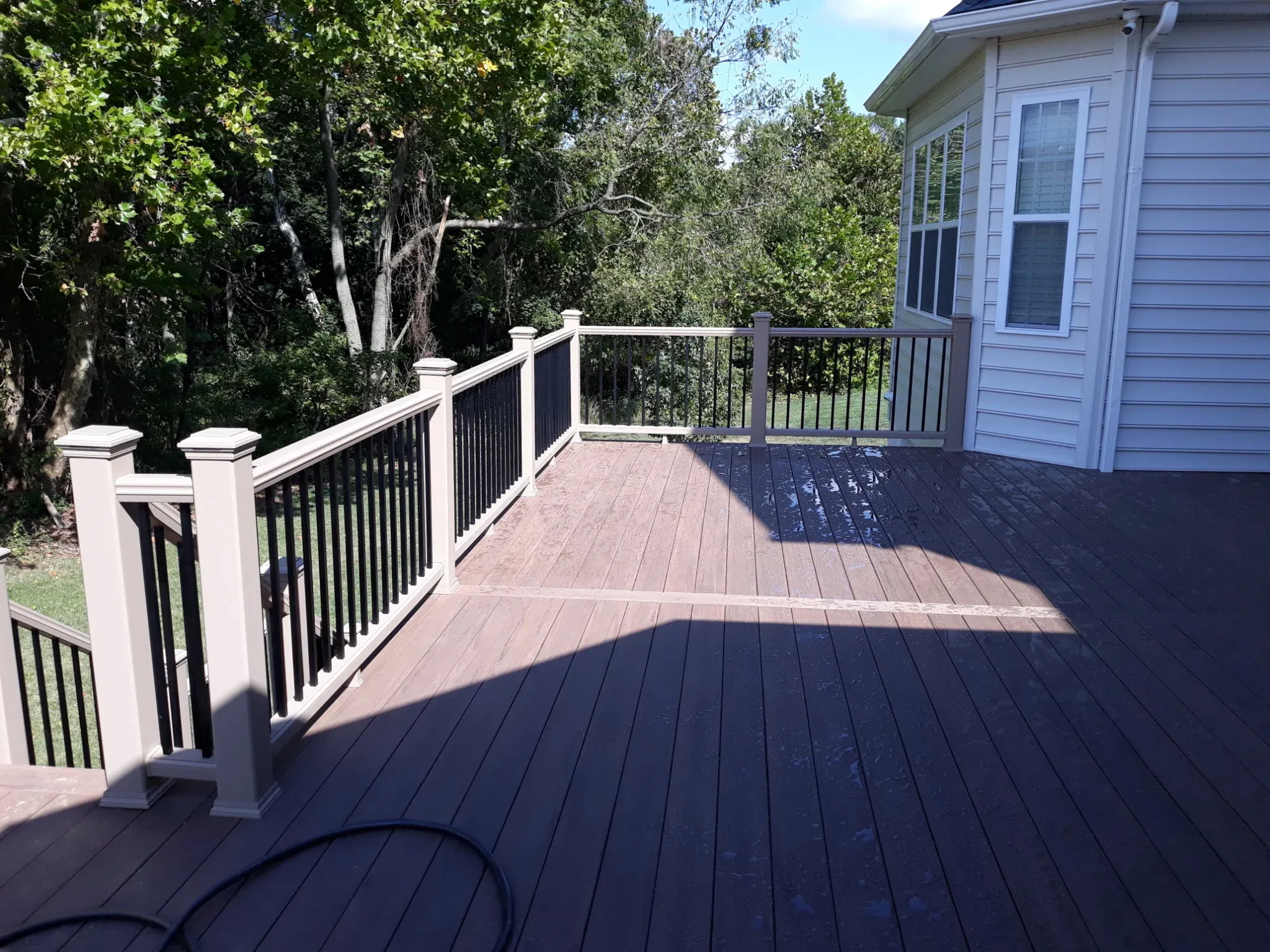 Large two-tone composite deck with black aluminum railing built off the back of a Delaware home by Zavala & Sons