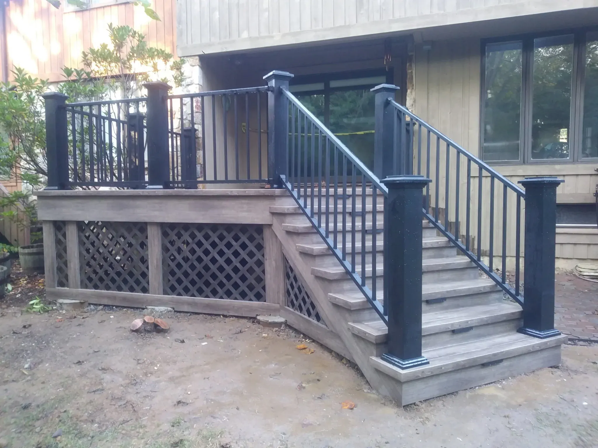 Gray composite deck with black aluminum railings, side stairs and lattice skirt by Zavala & Sons in Delaware