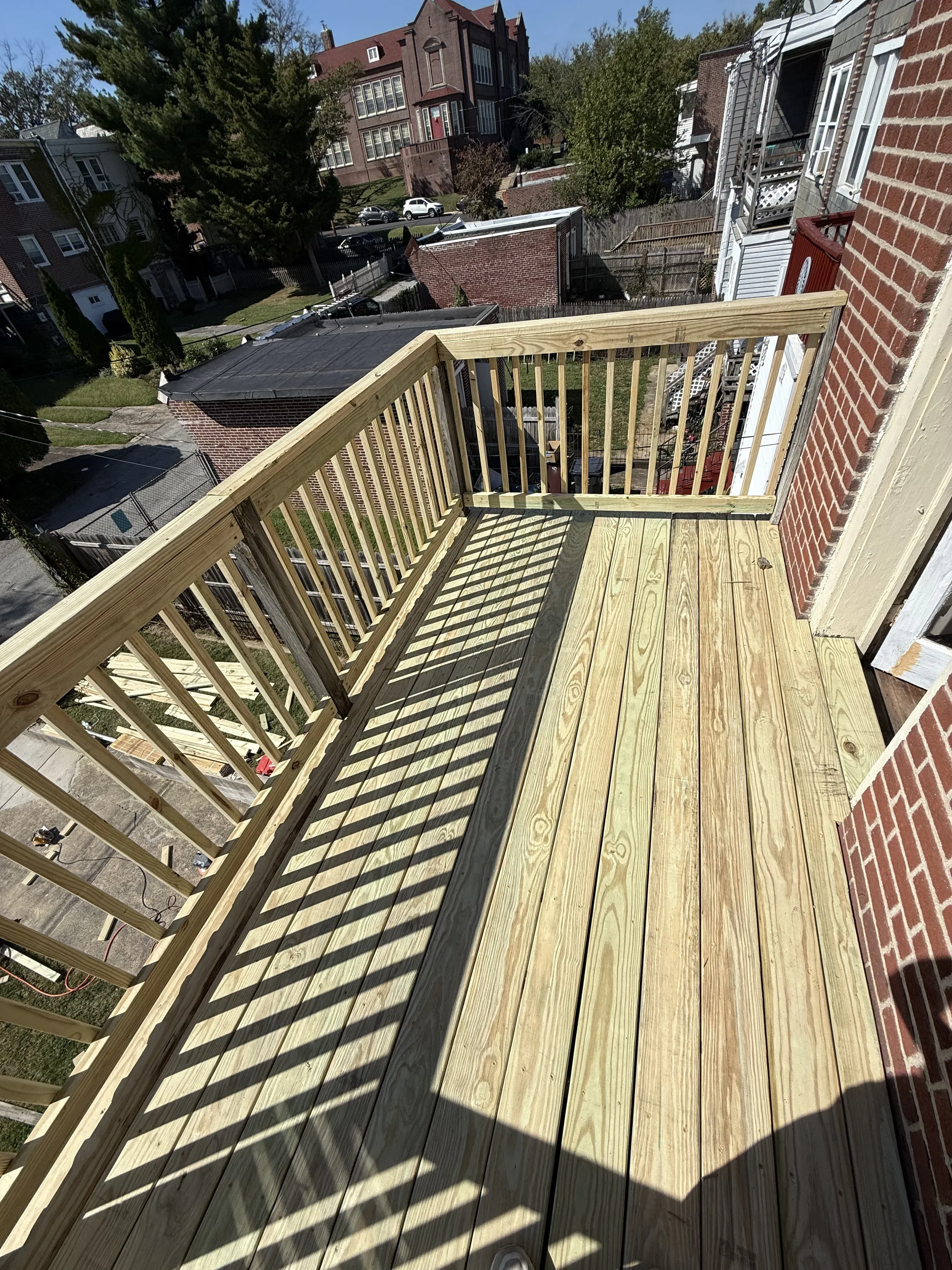 Pressure-treated wood deck balcony with vertical baluster railing overlooking neighborhood — Zavala & Sons deck construction