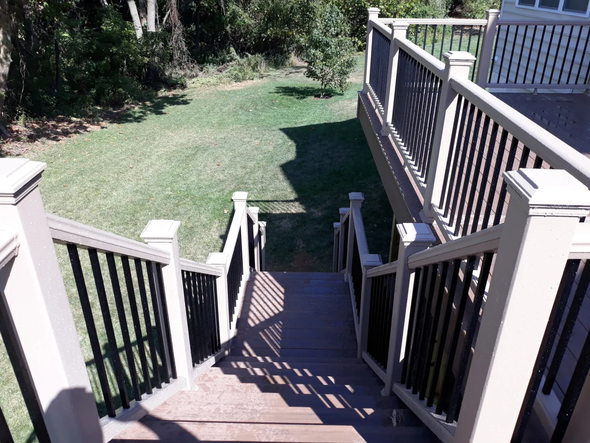 Overhead view of composite deck stairs leading to backyard lawn — outdoor living project by Zavala & Sons