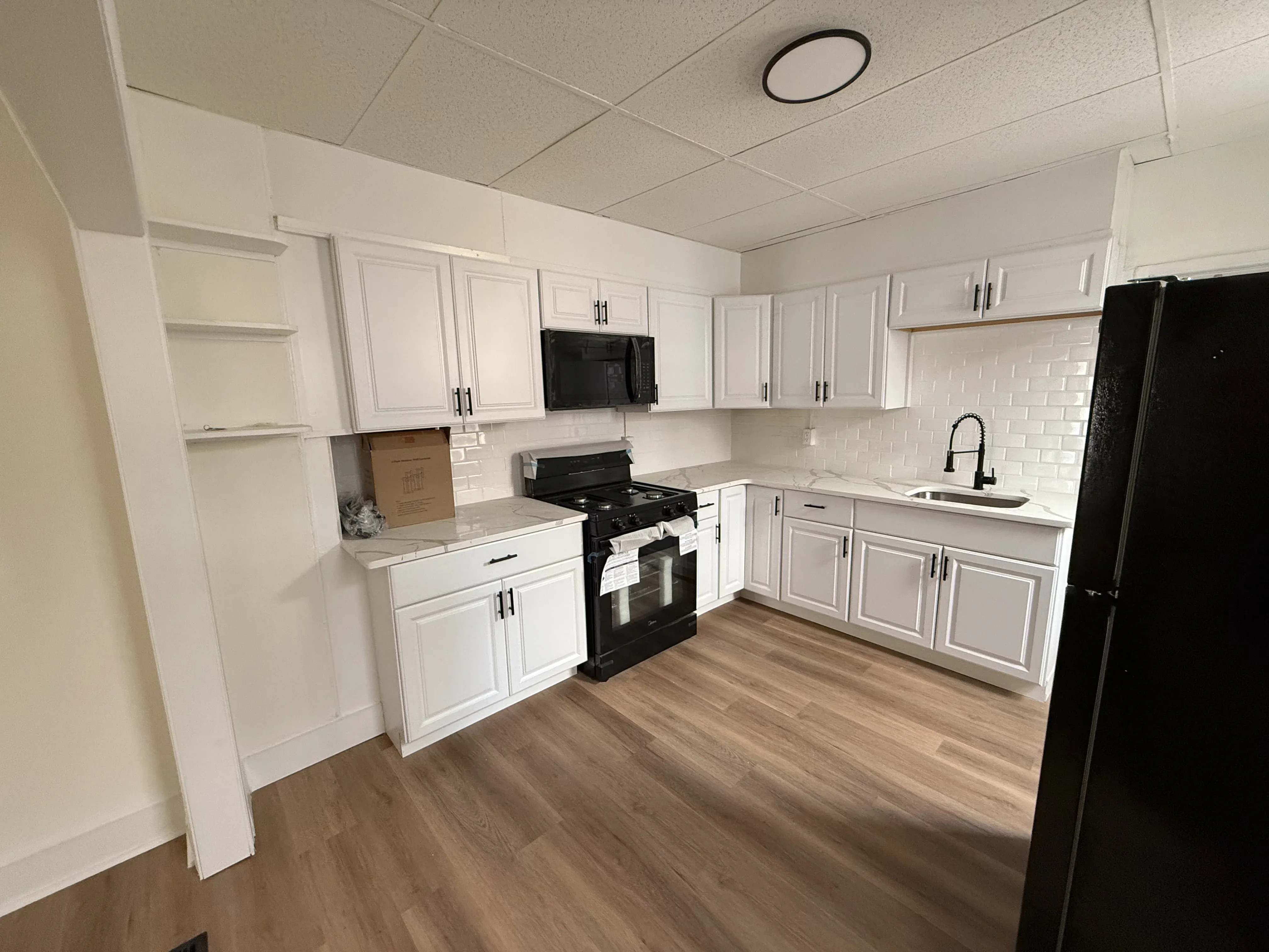 Compact galley kitchen renovation with white shaker cabinets, subway tile backsplash and black appliances — Wilmington DE home improvement