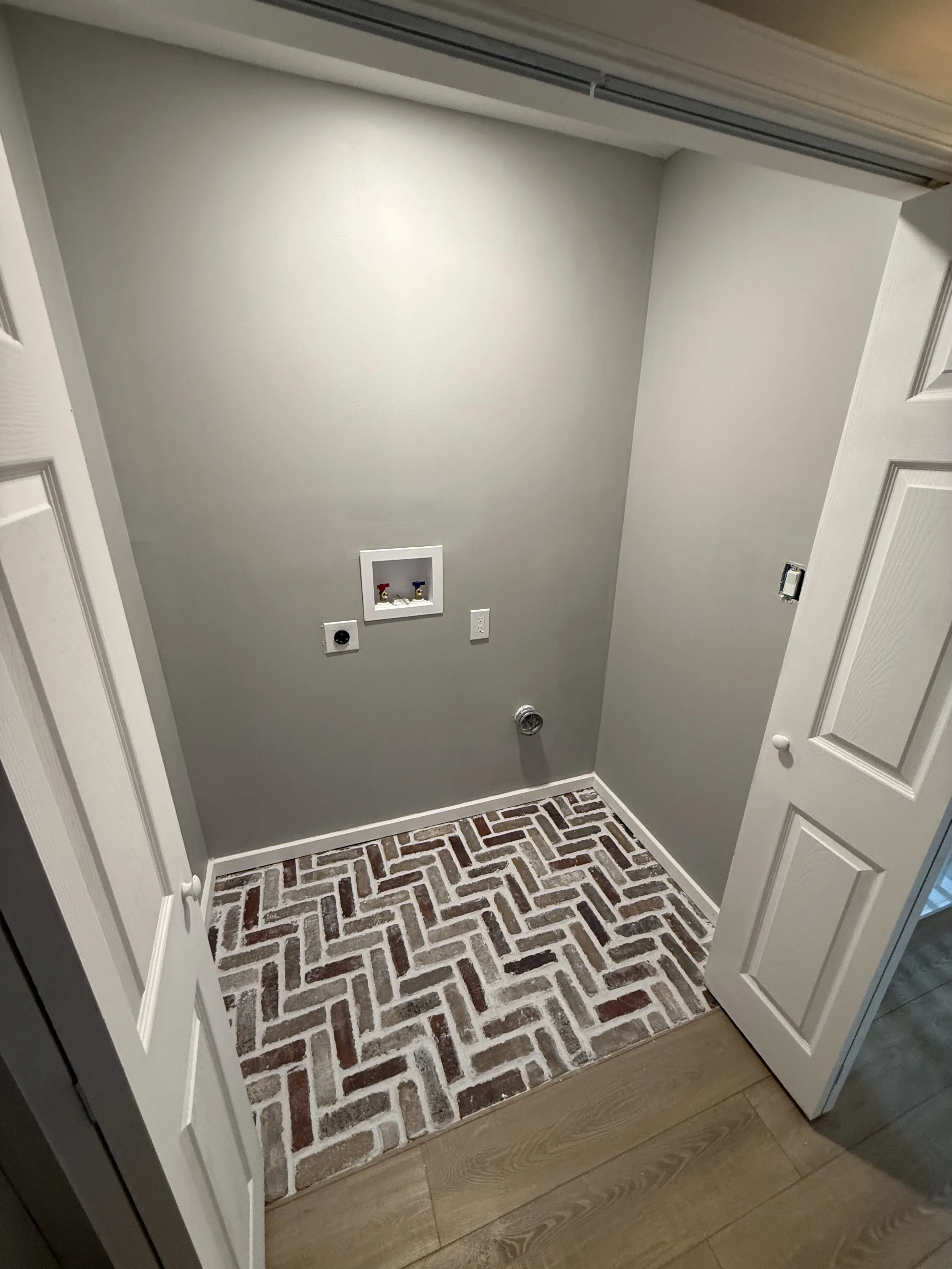 Laundry room remodel with red herringbone brick tile floor, fresh paint and new washer/dryer hookups by Zavala & Sons