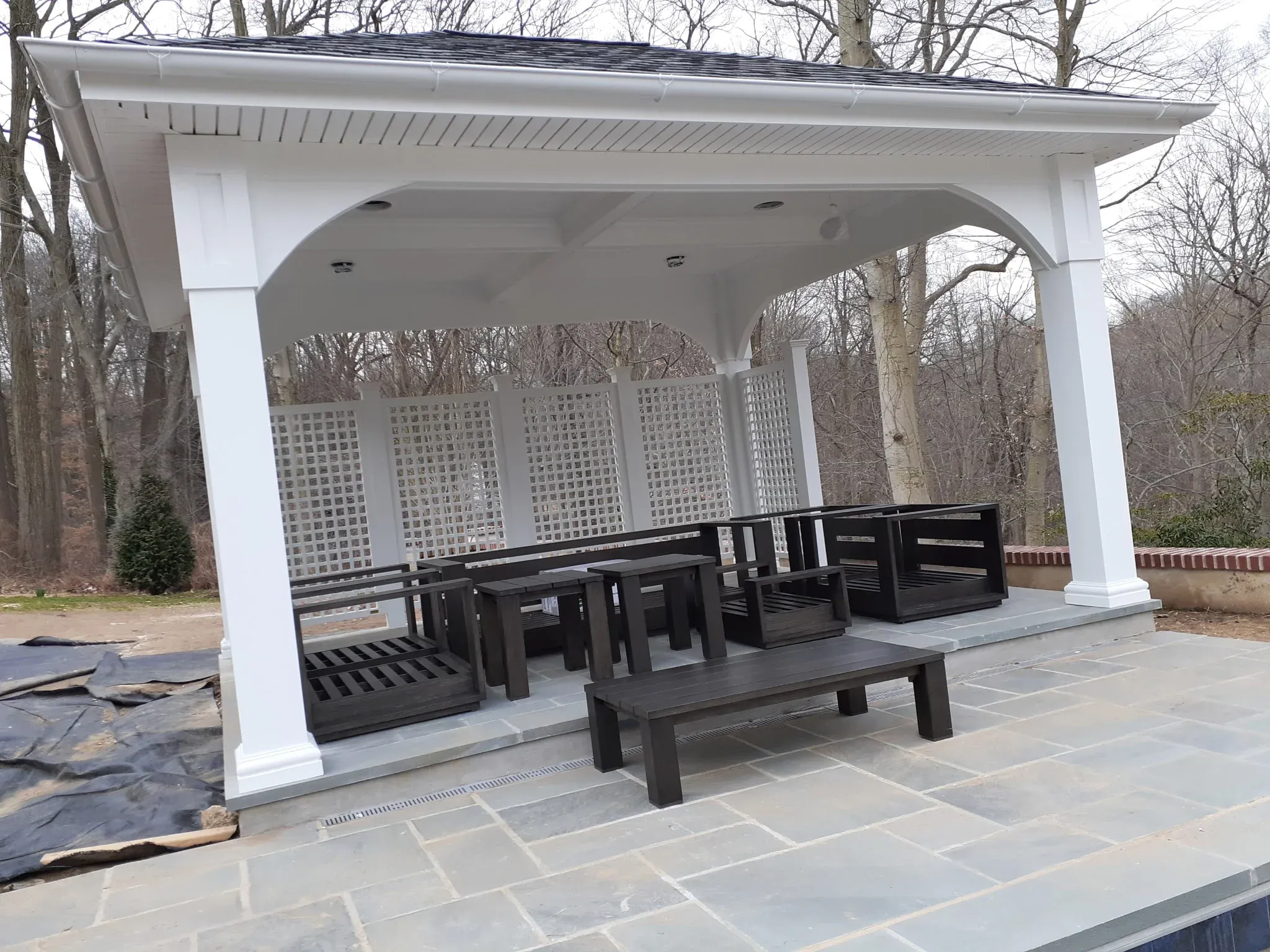 Custom outdoor pavilion with hip roof, bench seating and bluestone patio floor — premium outdoor living by Zavala & Sons